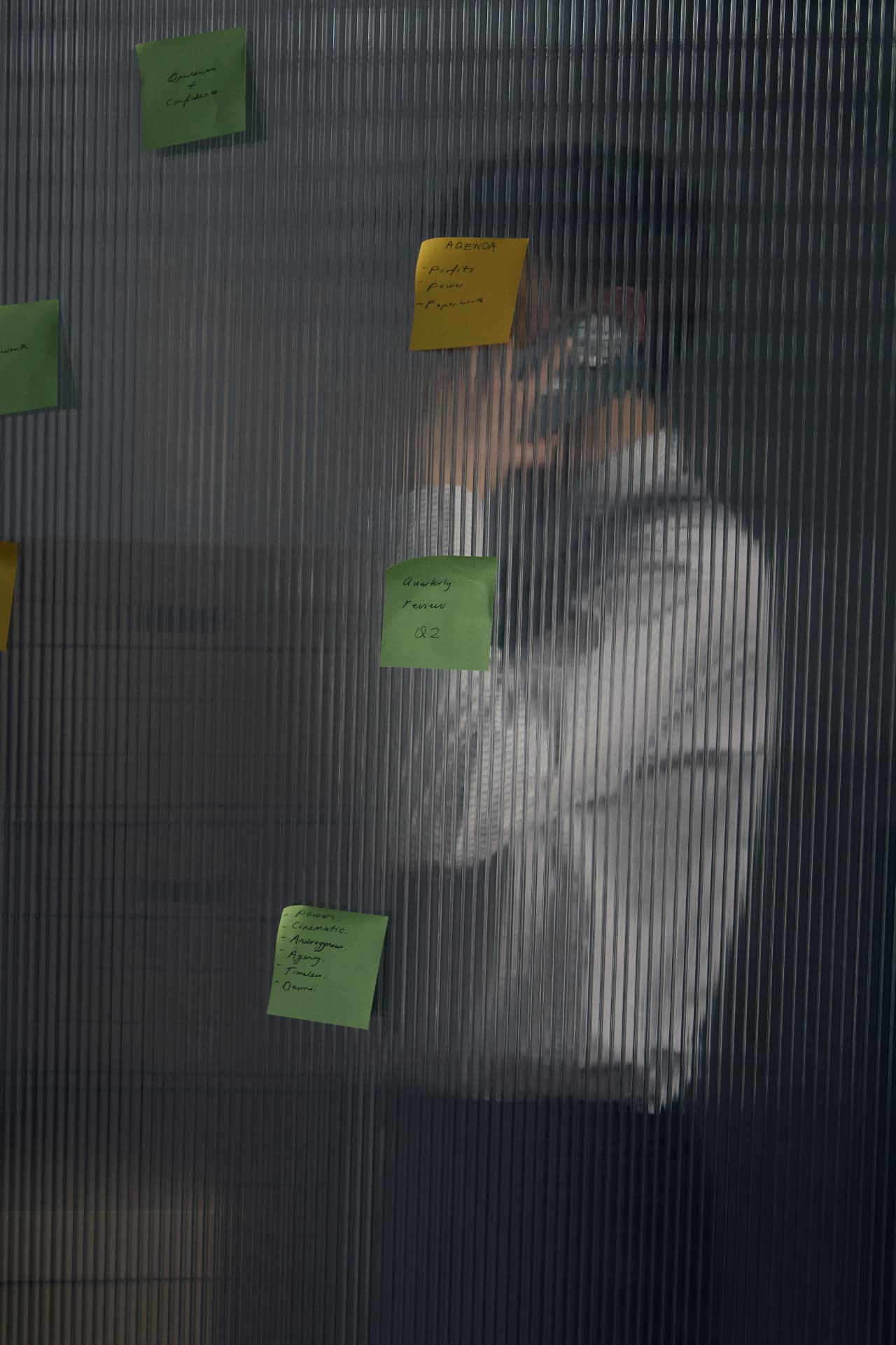 Sticky notes with a meeting agenda on a ribbed glass wall