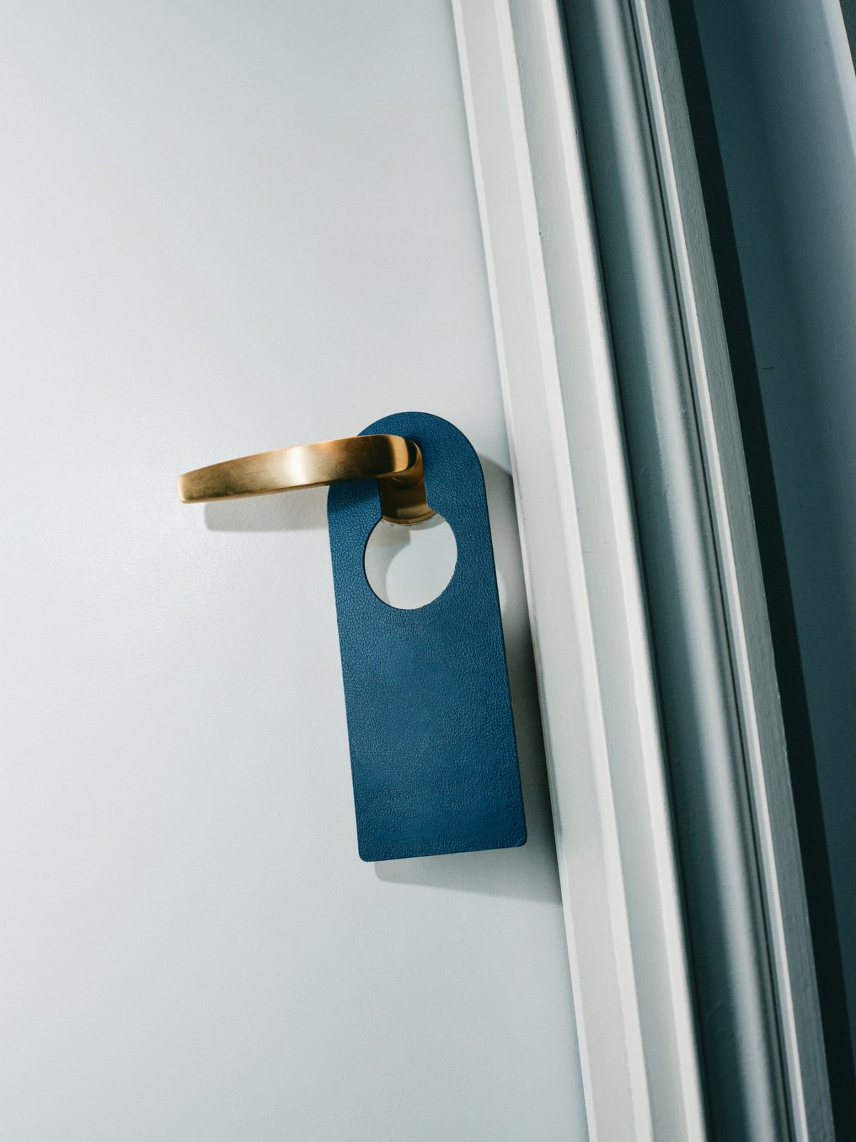 A leather do-not-disturb sign on a brass door handle